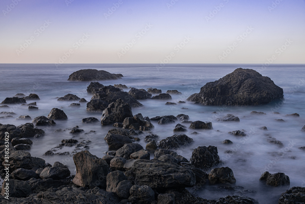 Volcanic rocks in Atlantic ocean, long exposure photography, horizon with sunset light, San Juan de la Rambla coastline, Tenerife, Canary islands, Spain Volcanic rocks in Atlantic ocean, long exposure photography, horizon with sunset light, San Juan de la Rambla coastline, Tenerife, Canary islands, Spain
