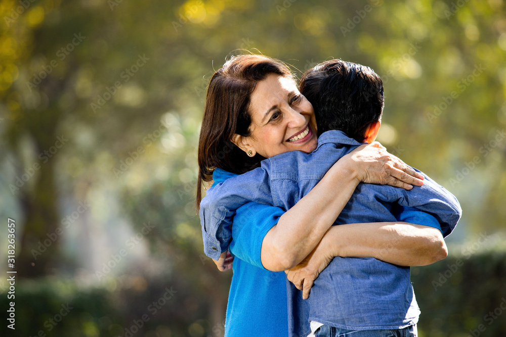 Fototapeta premium Woman embracing grandson at park