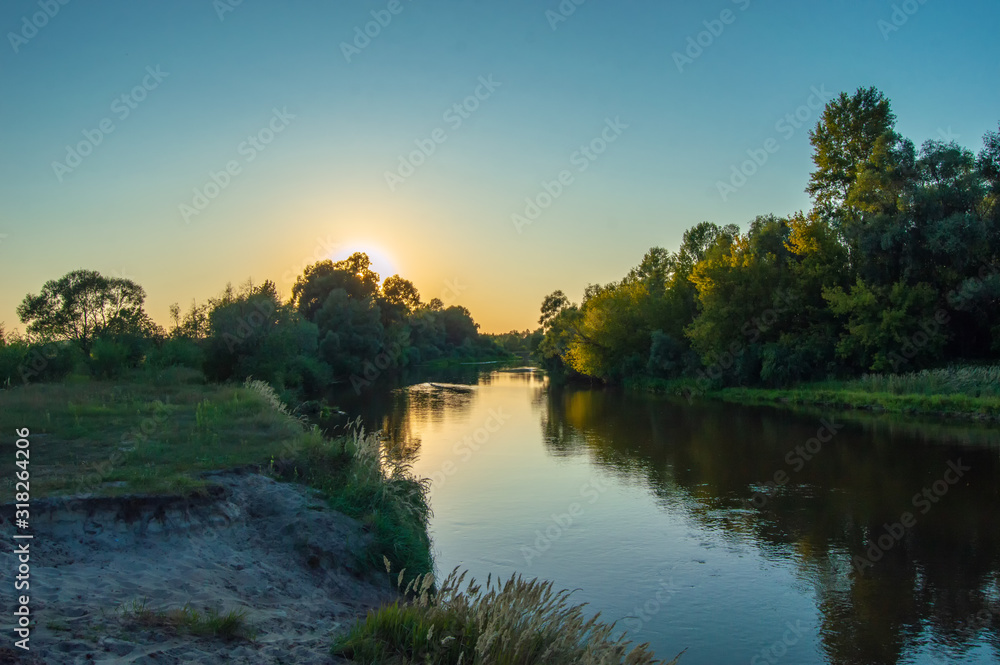 Sunset over the meandering river, which is hidden behind the crown of trees growing on the banks. Photos from the shore. Scenery of Teteriv river, which flows through Ukraine in Europe Sunset over the meandering river, which is hidden behind the crown of trees growing on the banks. Photos from the shore. Scenery of Teteriv river, which flows through Ukraine in Europe