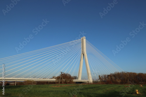 Rzeszow, Poland - 9 9 2018: Suspended road bridge across the Wislok River. Metal construction technological structure. Modern architecture. A white cross on a blue background is a symbol of the city