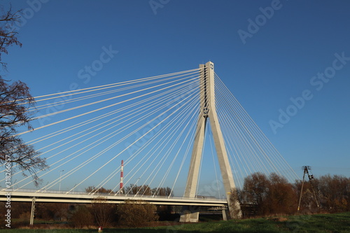 Rzeszow, Poland - 9 9 2018: Suspended road bridge across the Wislok River. Metal construction technological structure. Modern architecture. A white cross on a blue background is a symbol of the city © Xato Lux