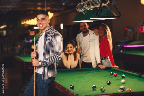 Group of friends play billiards at night out