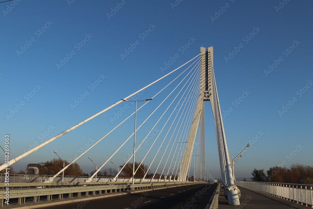 Fototapeta premium Rzeszow, Poland - 9 9 2018: Suspended road bridge across the Wislok River. Metal construction technological structure. Modern architecture. A white cross on a blue background is a symbol of the city
