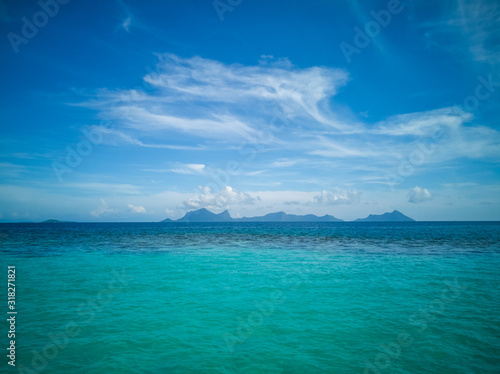 White sand beach turquoise sea water against blue sky with cloud seascape vacation background Semporna, Sabah.