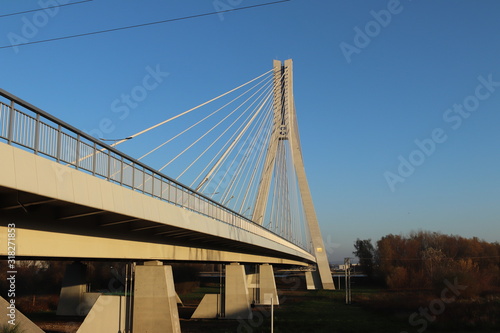Rzeszow, Poland - 9 9 2018: Suspended road bridge across the Wislok River. Metal construction technological structure. Modern architecture. A white cross on a blue background is a symbol of the city © Xato Lux