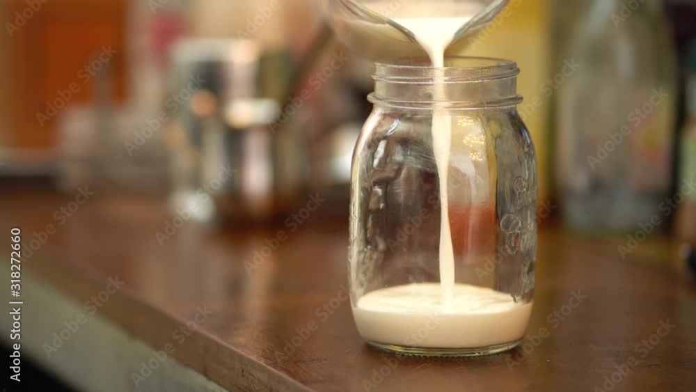 Pouring milk into measured cup in coffee shop Pouring milk into measured cup in coffee shop