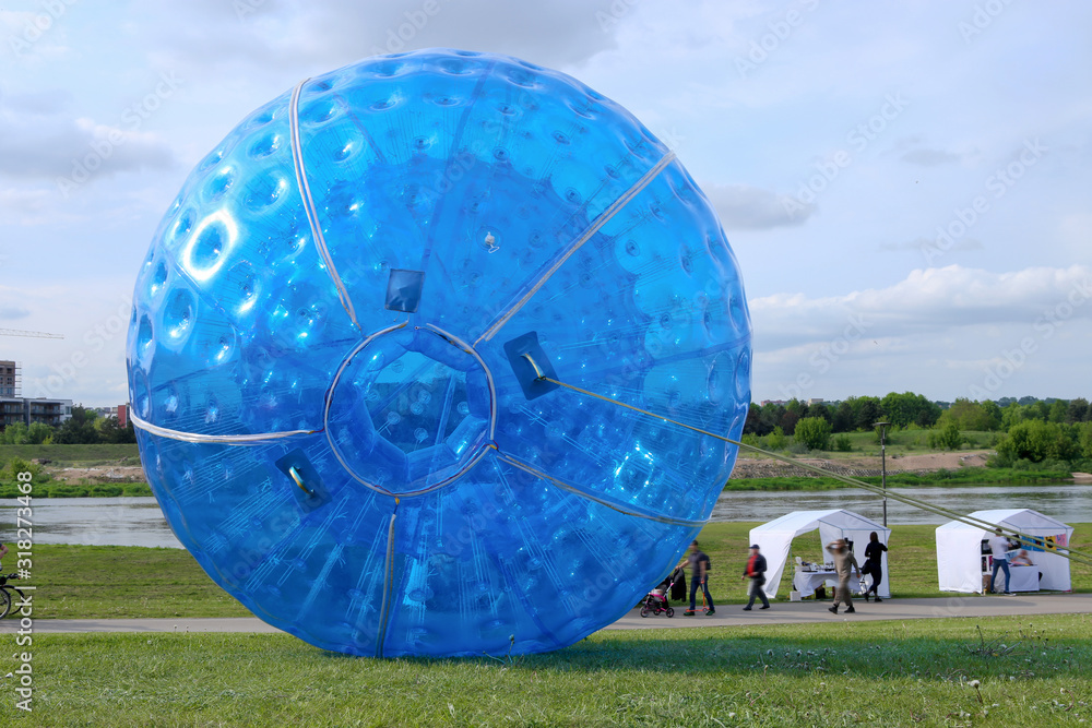 Two big blue zorbing ball in park. Big plastic bubble in grass field. Stock Photo Adobe Stock