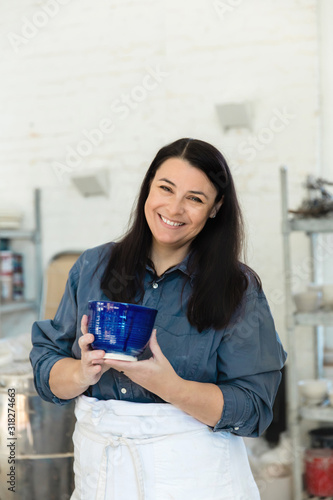 Creative Pottery Cermanic artist holding a blue piece of finished and glazed clay pottery in an art loft studio photo