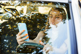 Careless female driver using smartphone while driving a car. Dangerous style of driving a car by young lady. Addiction of communicating in social media