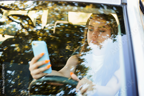 Tablou pe pânză Careless female driver using smartphone while driving a car