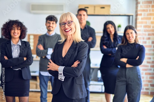 Group of business workers smiling happy and confident. Posing together with smile on face looking at the camera, middle age beautiful woman with crossed arms at the office