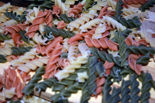 Multi-colored pasta on a wooden board. Food.