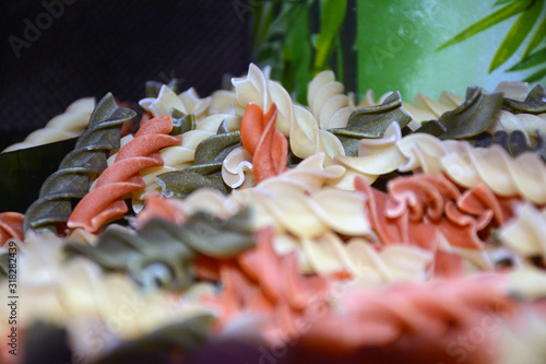 Multi-colored pasta on a wooden board. Food.