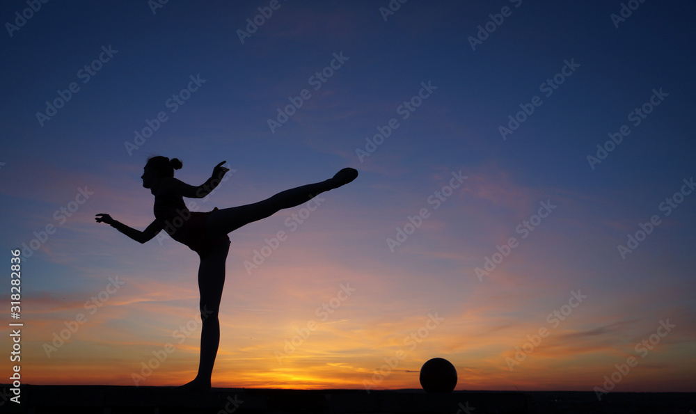 dancer in the dance does the splits in the air against the sunset