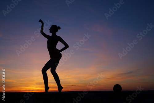 Fototapeta Naklejka Na Ścianę i Meble -  dancer in the dance does the splits in the air against the sunset