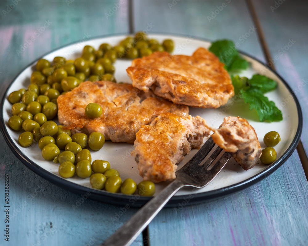 Breakfast of chum salmon cutlets with green peas and a fork Breakfast of chum salmon cutlets with green peas and a fork