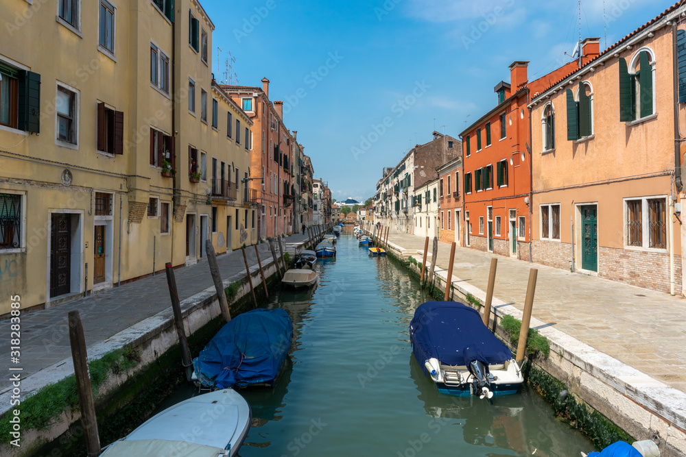 Venice, Italy. View of Venice. Venetian old colorful buildings against blue sky and white clouds. Jetty. Boat trip through the canals of Venice. Vacation in Europe concept.