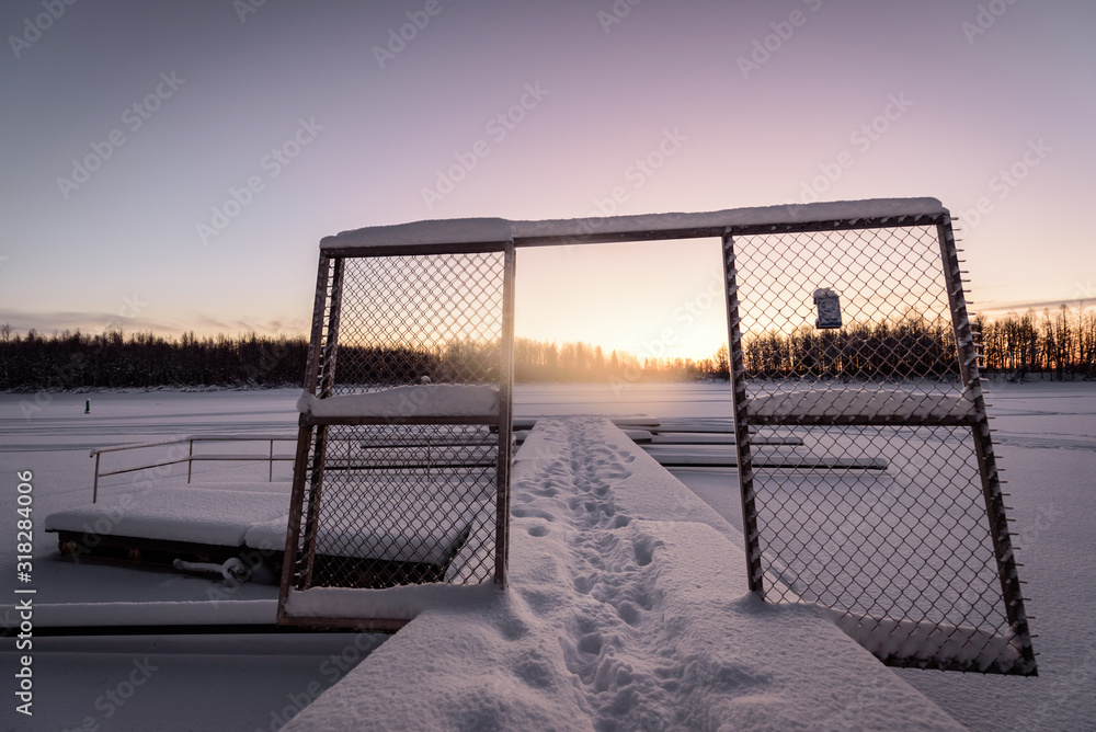 Fototapeta premium The ice lake and forest has covered with heavy snow and nice blue sky in winter season at Holiday Village Kuukiuru, Finland.