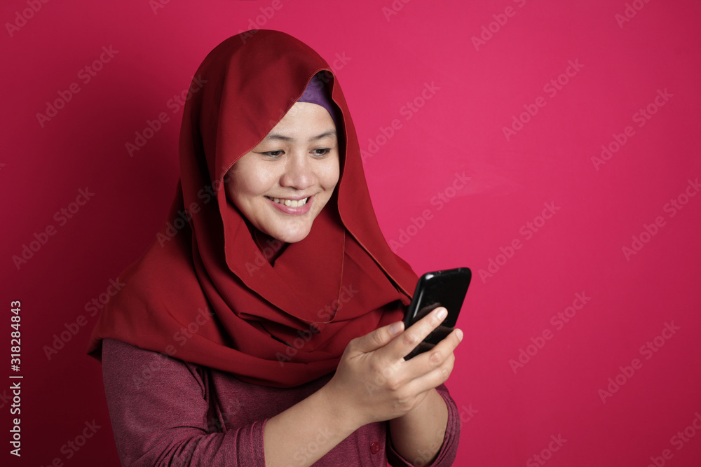 Muslim Woman Smiling While Reading Message on Smart Phone Muslim Woman Smiling While Reading Message on Smart Phone