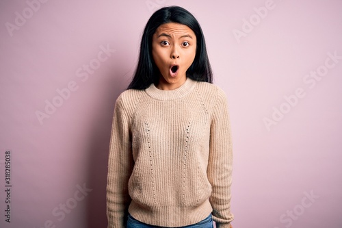 Fotografie Young beautiful chinese woman wearing casual sweater over isolated pink background afraid and shocked with surprise expression, fear and excited face