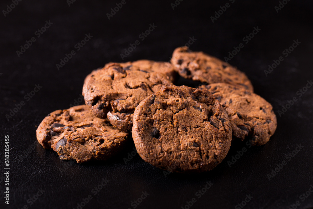 Fototapeta premium Appetizing chocolate chip cookies with slices of raisins on a black background.