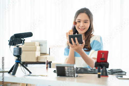Blogger,recording video tutorial online concept.Young Asian woman makeup artist youtuber influencer broadcasting demonstrating her cosmetic product live online.Female makeup beauty by eyebrow brush.
