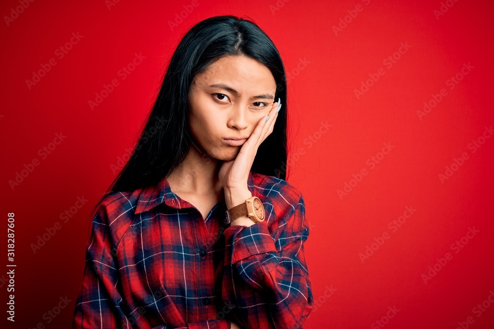 Young beautiful chinese woman wearing casual shirt over isolated red background thinking looking tired and bored with depression problems with crossed arms. Young beautiful chinese woman wearing casual shirt over isolated red background thinking looking tired and bored with depression problems with crossed arms.