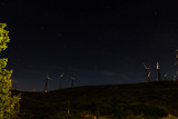 Group of white wind generators produces alternative energy by wind is on a black night sky with stars background