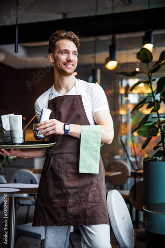 Smiling industrious waiter with napkin working in cafe photo