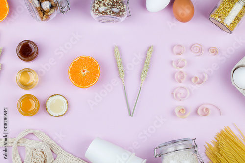 Word love made from jar with honey ,mandarin, wheat and wood shavings on pink background.