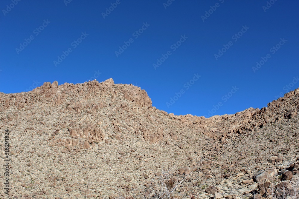 Below the deep blue Southern Mojave Desert sky rises ridges bounding Rattlesnake Canyon of Joshua Tree National Park. Below the deep blue Southern Mojave Desert sky rises ridges bounding Rattlesnake Canyon of Joshua Tree National Park.