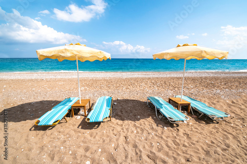 Fototapeta Naklejka Na Ścianę i Meble -  Empty sunbeds and umbrella on Afandou beach near Faliraki (Rhodes, Greece)