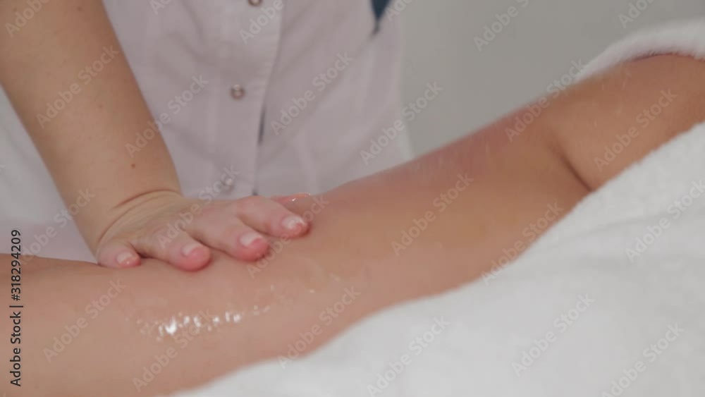 Woman massage therapist makes honey massage to a young girl in a massage parlor. Woman massage therapist makes honey massage to a young girl in a massage parlor.