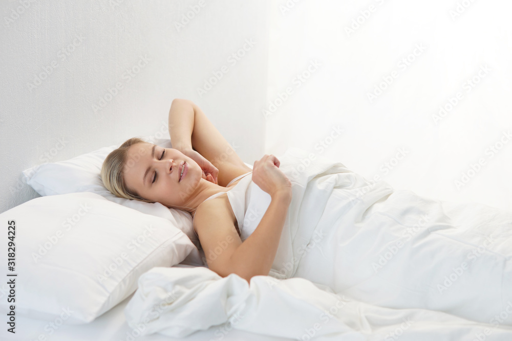 Young woman lying in the bed. Beautiful blond sleeping girl. Morning in the bedroom, daylight from the window. Health and rest. Young woman lying in the bed. Beautiful blond sleeping girl. Morning in the bedroom, daylight from the window. Health and rest.