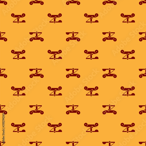 Billede på lærred Red Old medieval wooden catapult shooting stones icon isolated seamless pattern on brown background