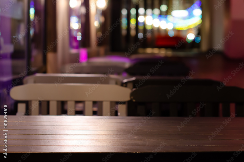 Image of wooden table in front of abstract blurred restaurant lights background in evening Christmas decoration.