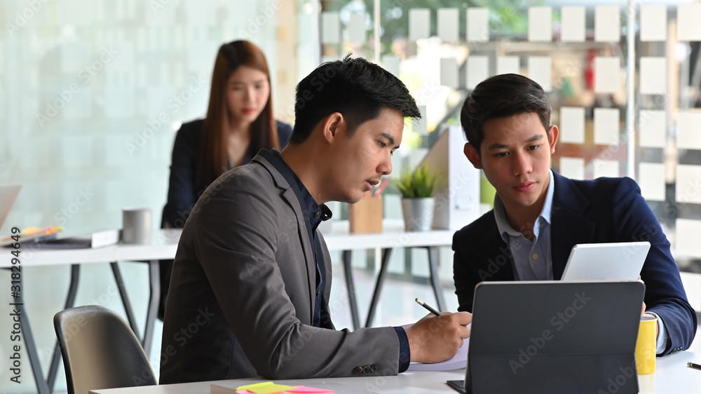 Business executive discussing about them business plan at the meeting table with beautiful employee girl as background. Business executive discussing about them business plan at the meeting table with beautiful employee girl as background.