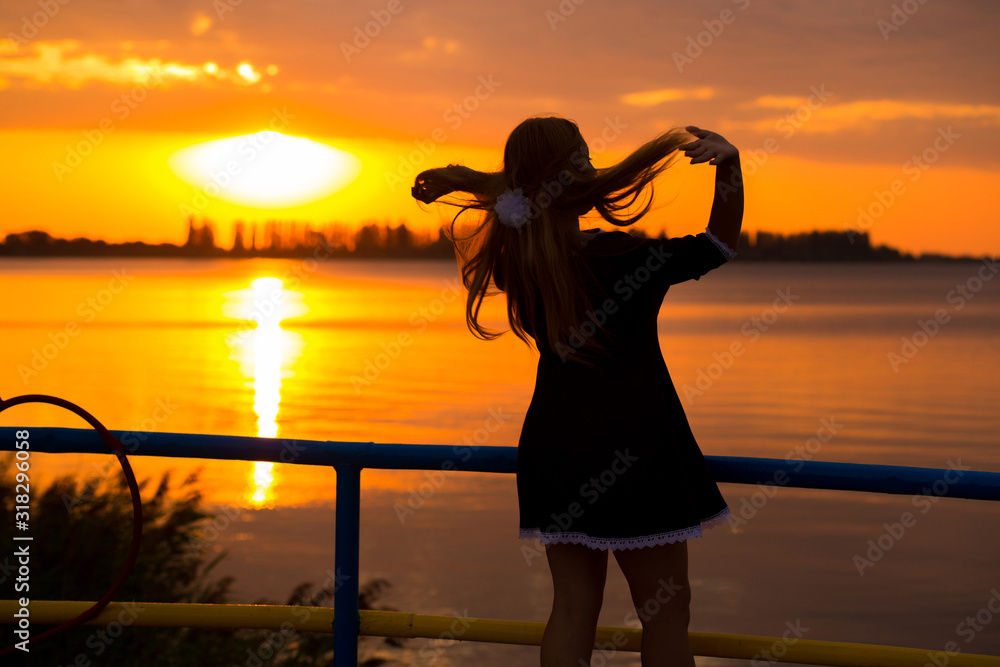 Side view of back light of a woman silhouette breathing deep fresh air at warm sunrise in front of sun. female lightness and airiness