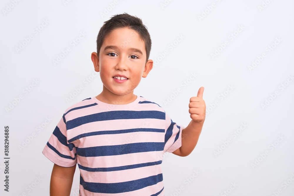 Beautiful kid boy wearing casual striped t-shirt standing over isolated white background doing happy thumbs up gesture with hand. Approving expression looking at the camera showing success. Beautiful kid boy wearing casual striped t-shirt standing over isolated white background doing happy thumbs up gesture with hand. Approving expression looking at the camera showing success.