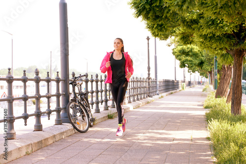 Sporty young woman running on the street early morning photo