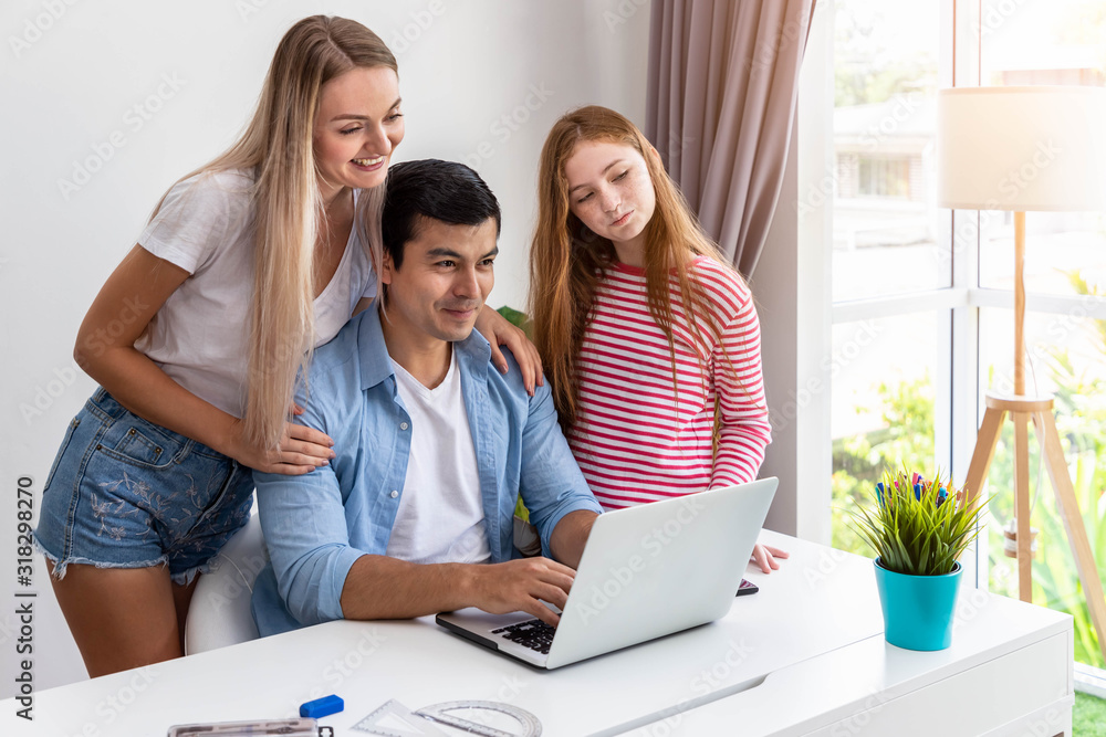 Obraz premium Man or father is working at home using computer notebook, with daughter, embrace by woman mother