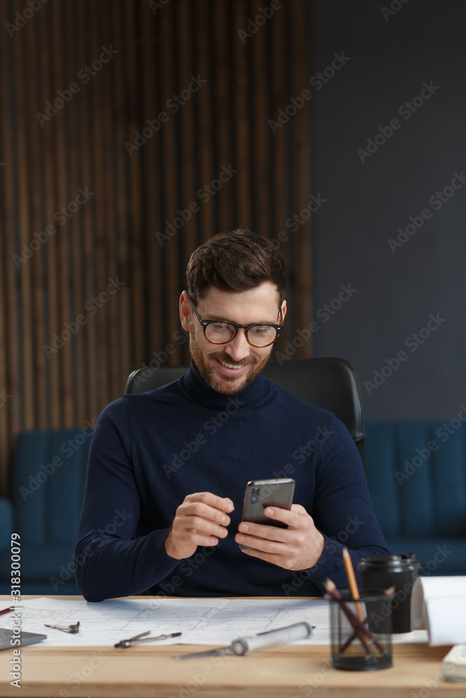 Young man using smartphone and smiling. Happy businessman using mobile phone apps, texting message, browsing internet, looking at smartphone. Concept of young people working with mobile devices. Young man using smartphone and smiling. Happy businessman using mobile phone apps, texting message, browsing internet, looking at smartphone. Concept of young people working with mobile devices.