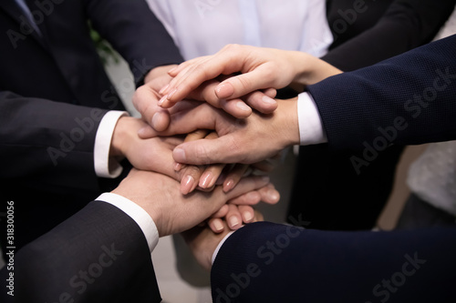Close up diverse business people stacking hands together showing unity.