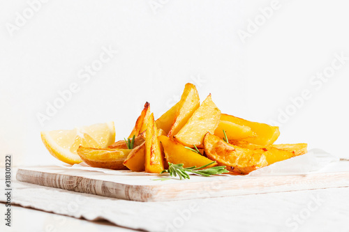 Homemade baked potato fries with rosemary on white wooden board