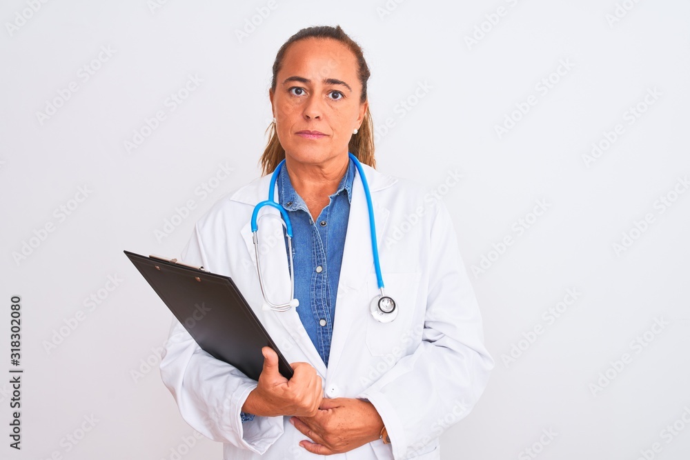Middle age mature doctor woman holding clipboard over isolated background with a confident expression on smart face thinking serious Middle age mature doctor woman holding clipboard over isolated background with a confident expression on smart face thinking serious