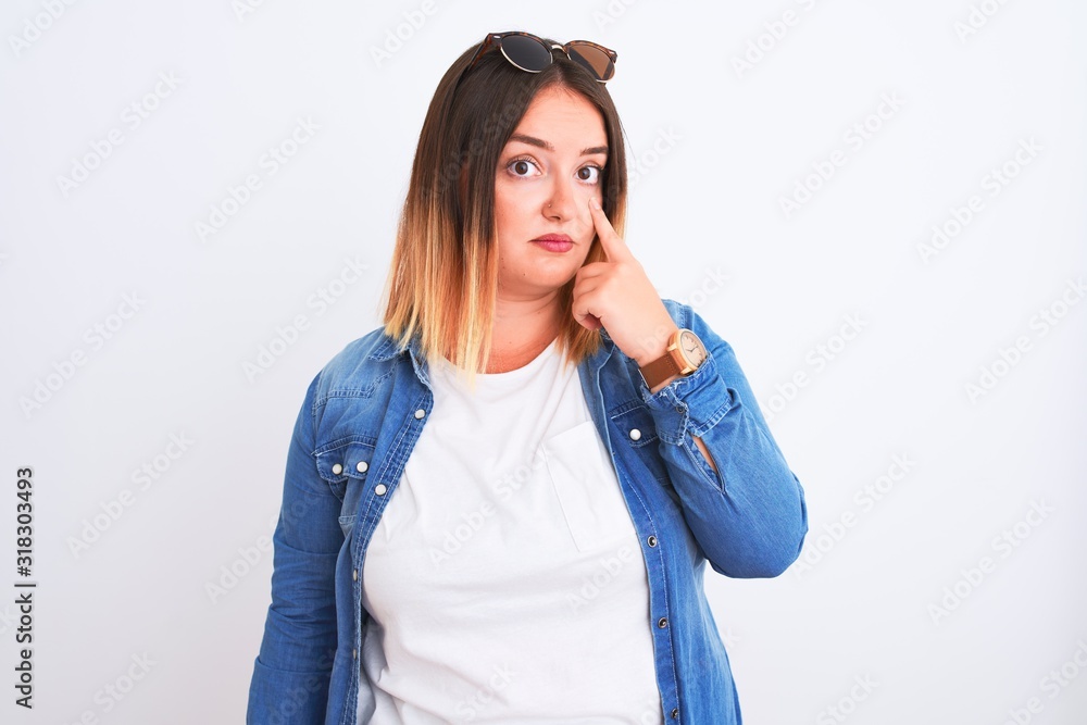 Beautiful woman wearing denim shirt standing over isolated white background Pointing to the eye watching you gesture, suspicious expression Beautiful woman wearing denim shirt standing over isolated white background Pointing to the eye watching you gesture, suspicious expression