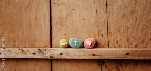Kommunion, Konfirmation, Firmung, Taufe - bunte Steine mit Kreuz, Fisch und Herz auf Holz photo