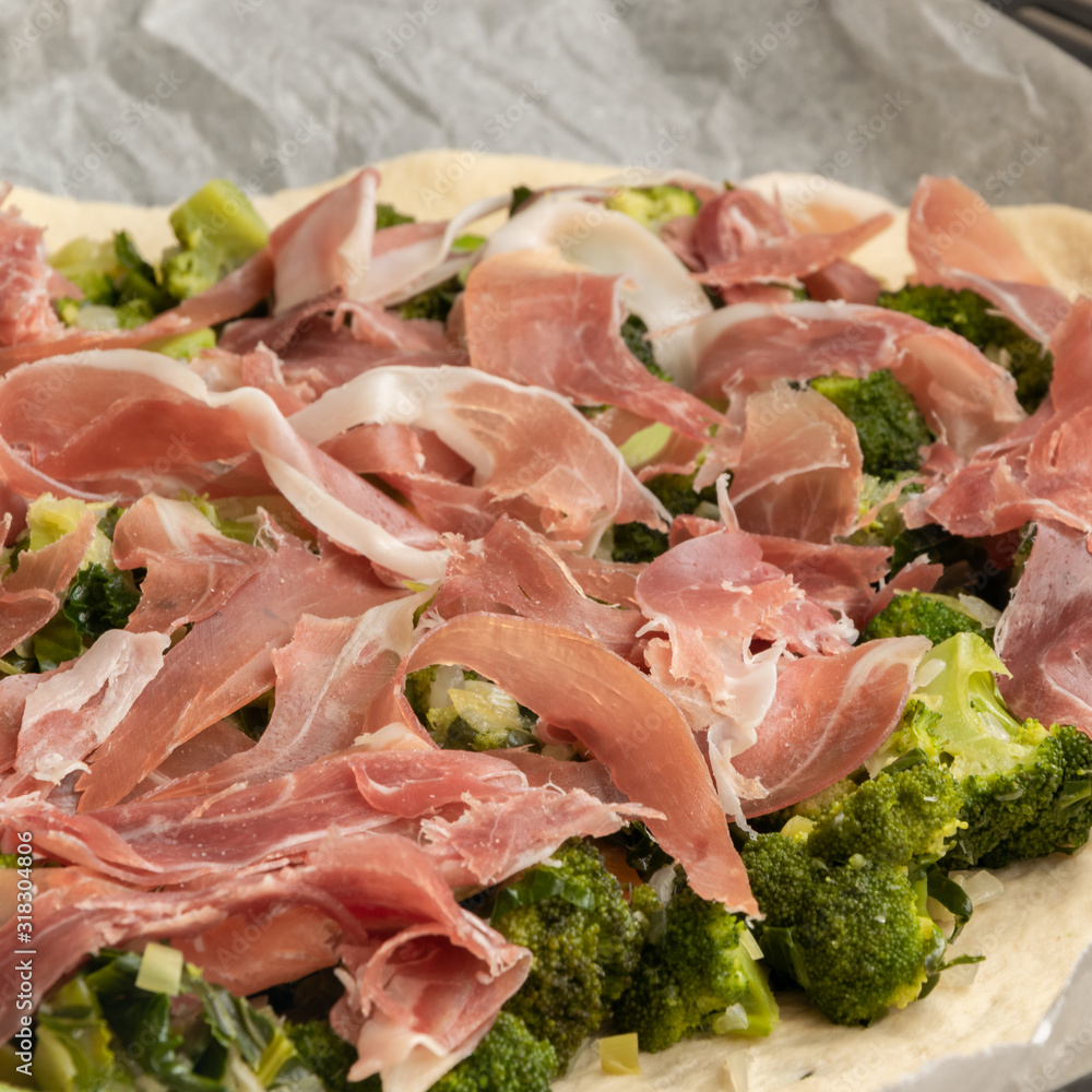 Preparing homemade pizza with vegetables and raw ham Preparing homemade pizza with vegetables and raw ham