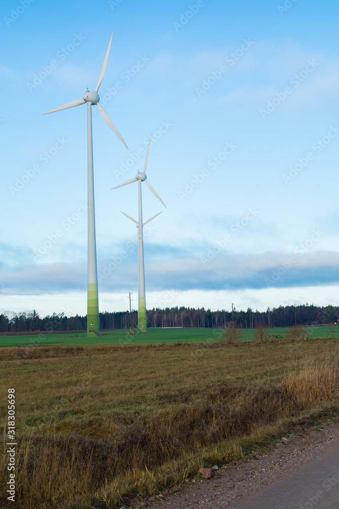 Wind electricity generator park, visible green farming fields, trees, grass and blue skies with clouds Wind electricity generator park, visible green farming fields, trees, grass and blue skies with clouds