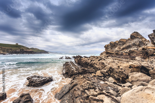 Tagle beach in winter with dramatic sky and waves against the rocks photo